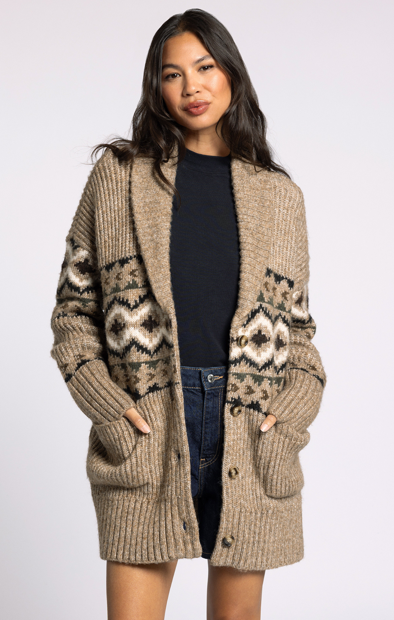 Woman wearing a beige knitted cardigan with patterned sleeves on a white background