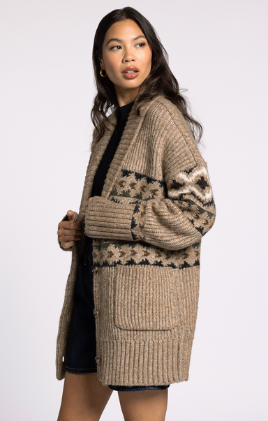 Woman wearing a beige cardigan with a pattern on a white background
