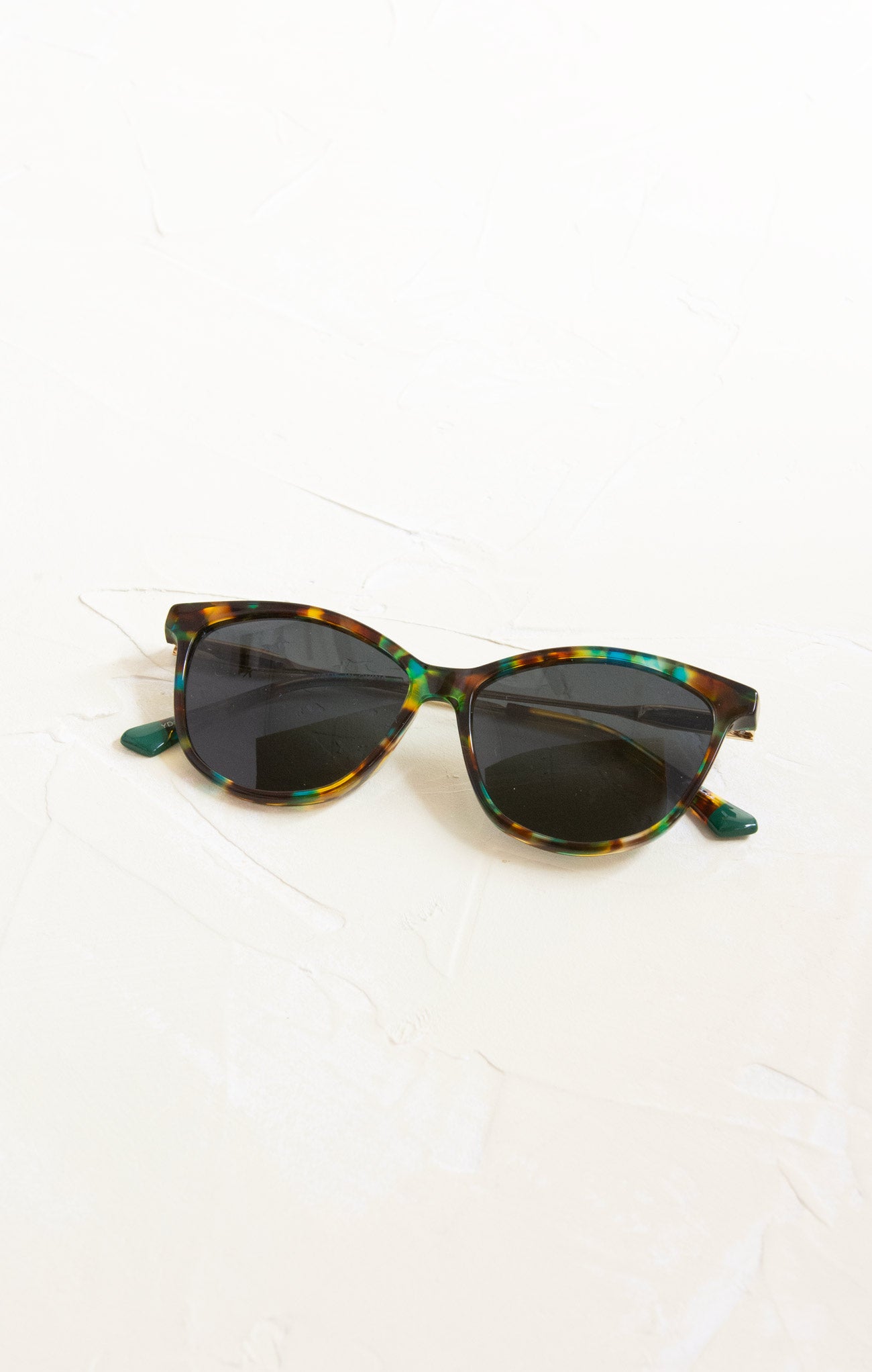 Sunglasses with tortoiseshell frame and dark lenses on a white background