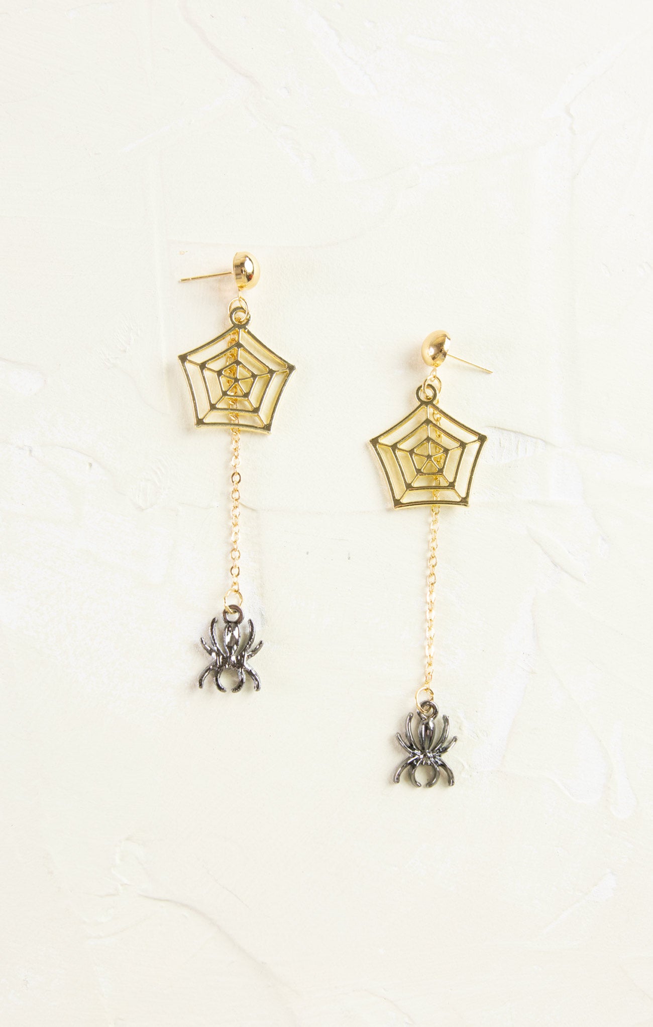 Gold spiderweb earrings with spider charms on a white background