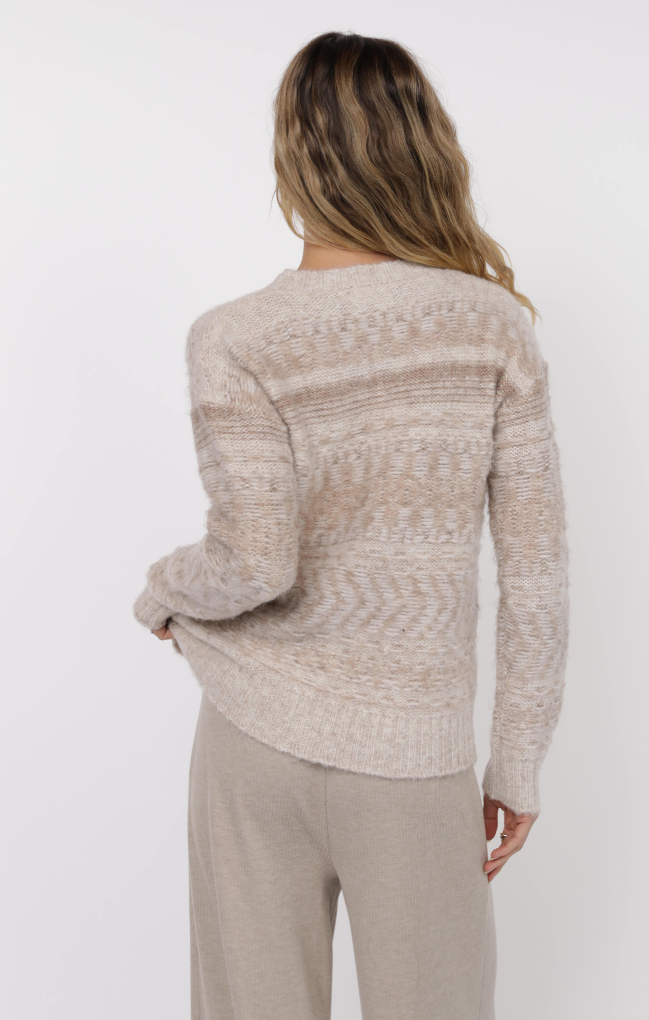 Woman wearing a beige sweater and pants on a white background