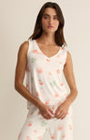 Woman wearing a white sleeveless top with floral pattern on a plain background