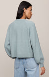 Person wearing a light blue sweater and jeans against a plain background