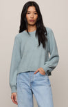 Woman wearing a light blue sweater and jeans against a plain background