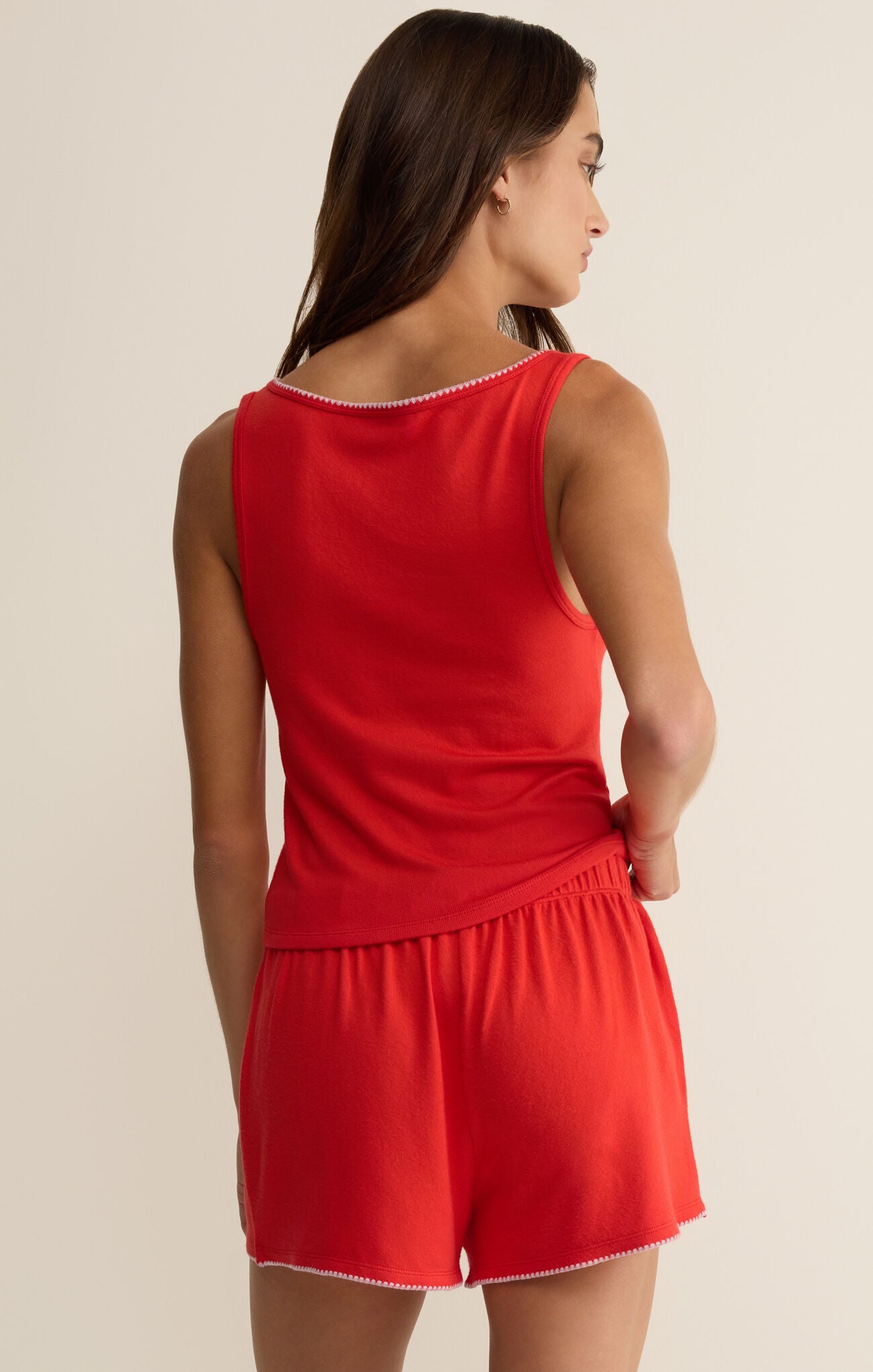 Woman wearing a red romper with a plain background