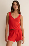 Woman wearing a red tank top and shorts set against a beige background