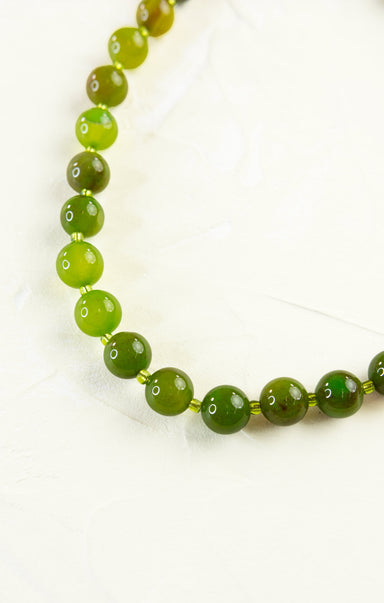 Green beaded necklace on a white background