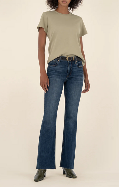 Person wearing a beige t-shirt and blue jeans on a plain background