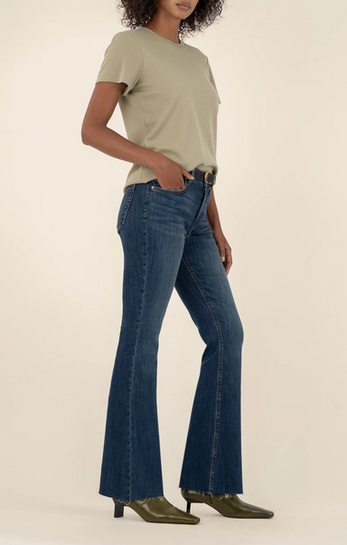 Person wearing a beige t-shirt and blue jeans on a plain background