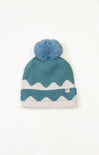 Teal knit beanie with white zigzag pattern and blue pom-pom on a white background