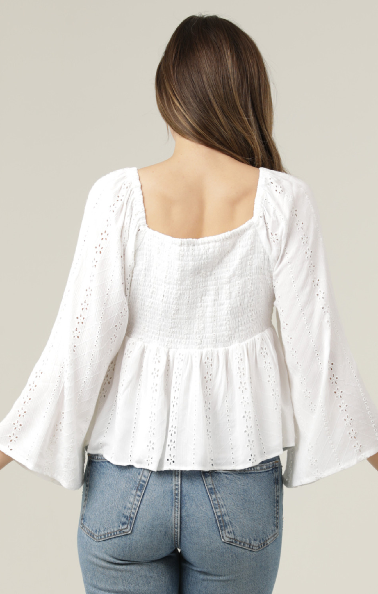 White blouse with bell sleeves worn by a person on a plain background