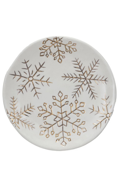 Round ceramic plate with gold snowflake patterns on a white background