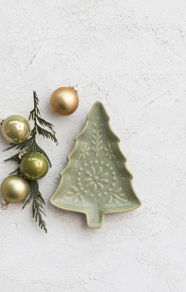 Green ceramic Christmas tree ornament with gold ornaments and greenery on a light gray background