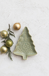 Green ceramic Christmas tree ornament with gold ornaments and greenery on a light gray background
