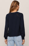 Person wearing a navy sweater with decorative buttons on a plain background