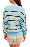 A woman shown from the back wearing a light blue knit sweater with horizontal black and beige stripes, paired with white lace shorts, against a plain white background.