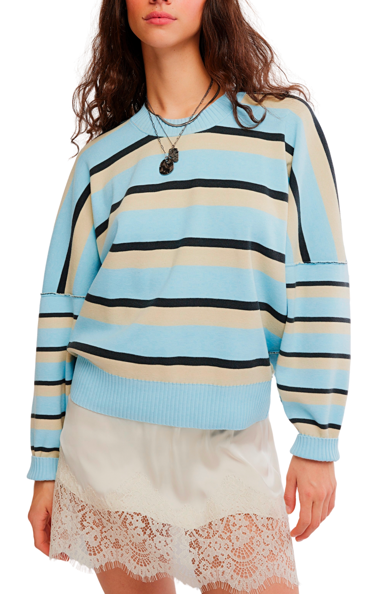 A woman wearing a light blue, beige, and black striped knit sweater with drop-shoulder sleeves, paired with cream lace-trim shorts, against a plain white background.