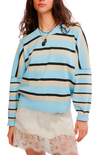 A woman wearing a light blue, beige, and black striped knit sweater with drop-shoulder sleeves, paired with cream lace-trim shorts, against a plain white background.