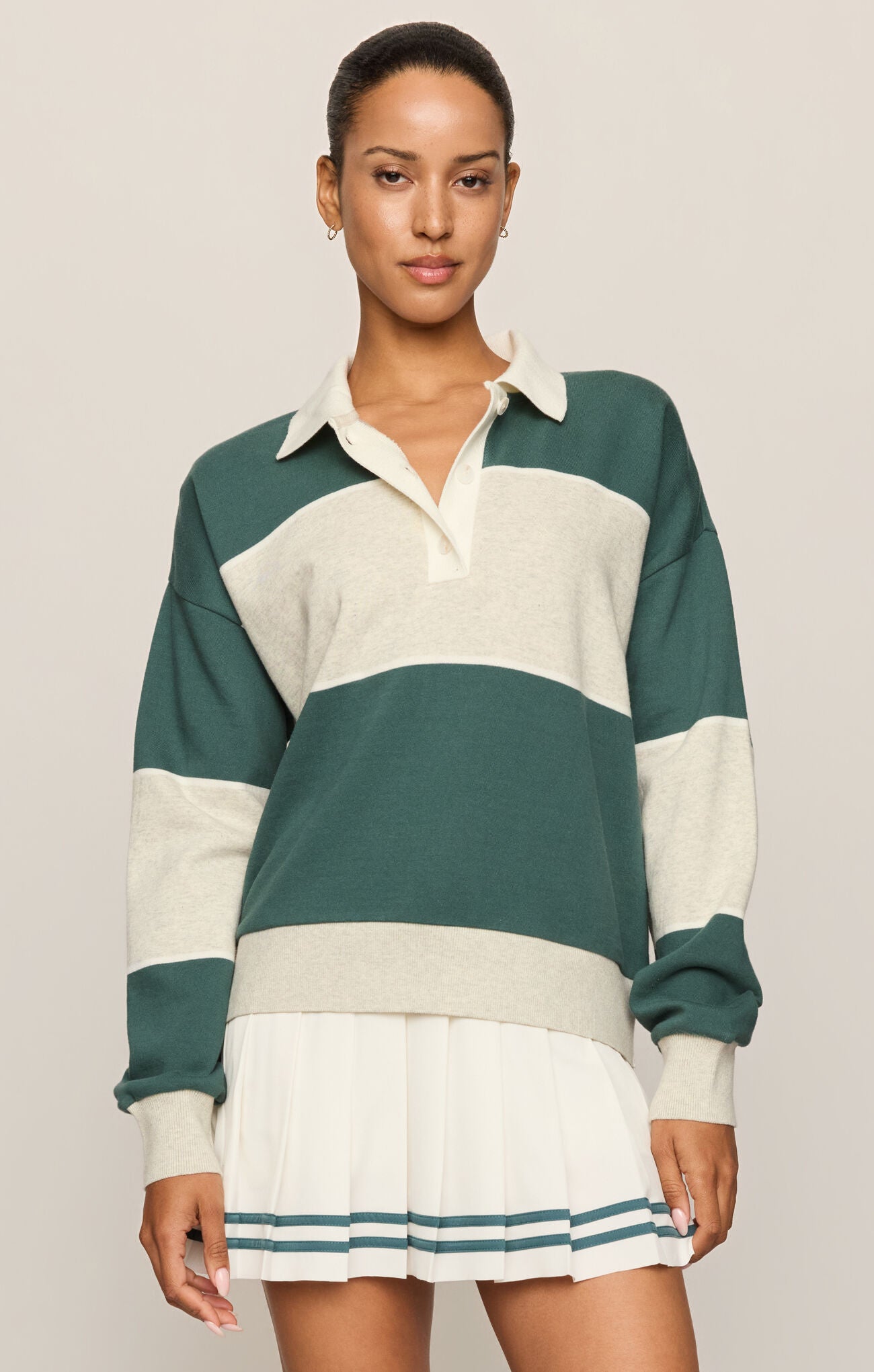 Woman wearing a green and white striped sweater with a matching skirt on a plain background