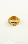 Gold ring with intricate design on a white background