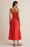 Woman wearing a strapless red dress against a beige background