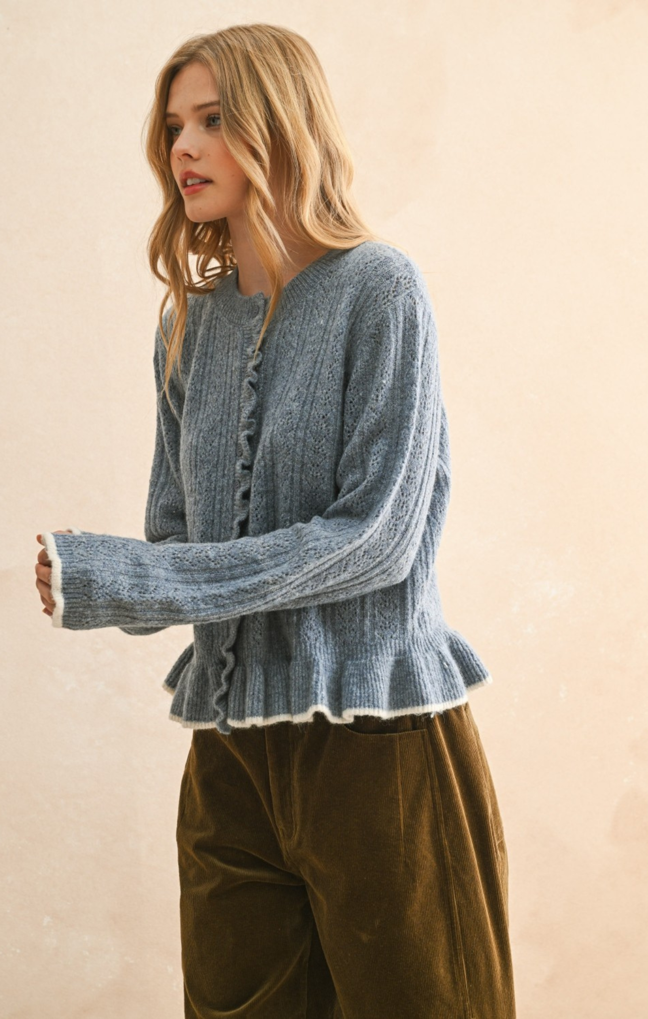 Woman wearing a blue knitted cardigan with a beige background