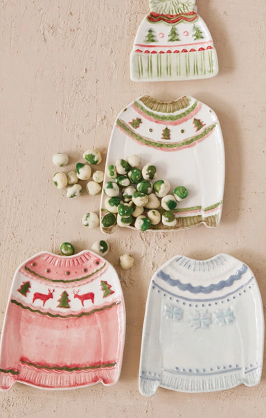 Four knitted sweater-shaped cookies on a textured surface