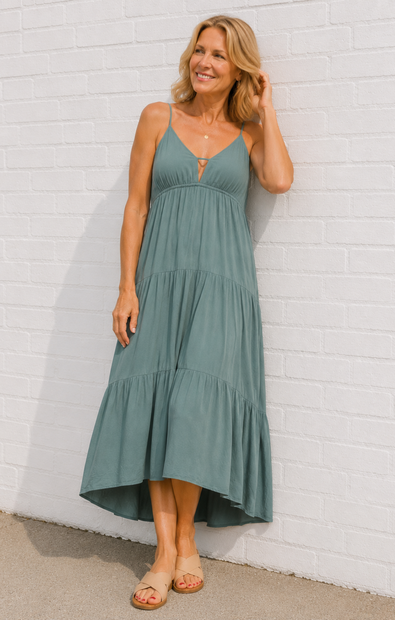 Woman wearing a green dress against a white brick wall