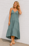 Woman wearing a green dress against a white brick wall