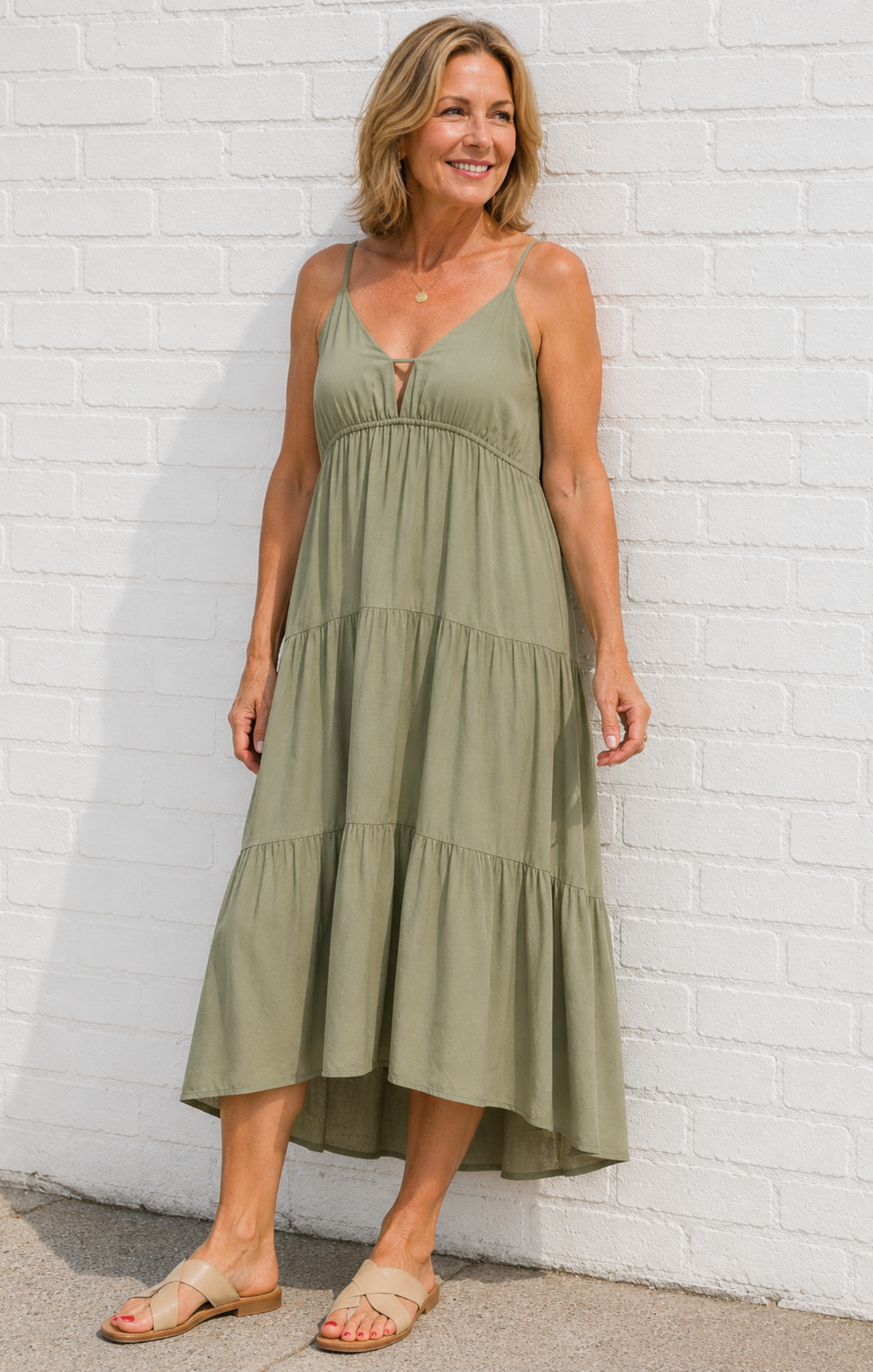 Woman wearing a green dress against a white brick wall