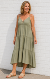 Woman wearing a green dress against a white brick wall