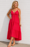 Woman wearing a red dress against a white brick wall