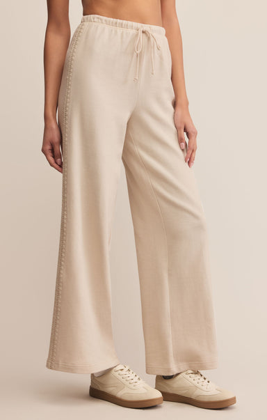 Person wearing beige wide-leg pants with a plain background