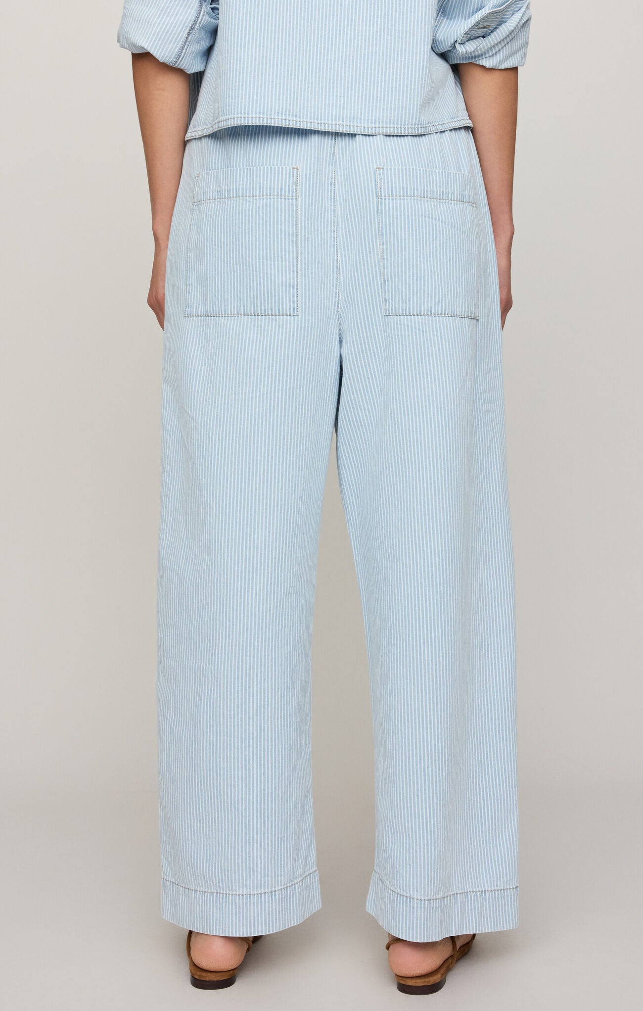 Light blue striped pants worn by a person on a beige background