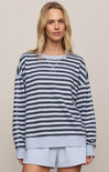 Woman wearing a striped sweater and light shorts against a neutral background