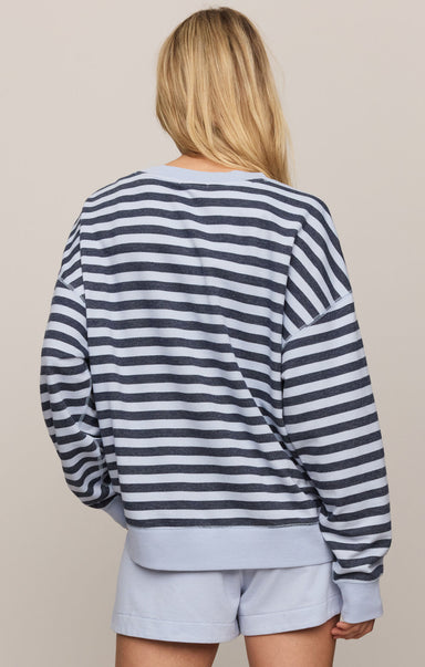 Person wearing a striped sweater and light blue shorts on a beige background