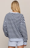 Person wearing a striped sweater and light blue shorts on a beige background