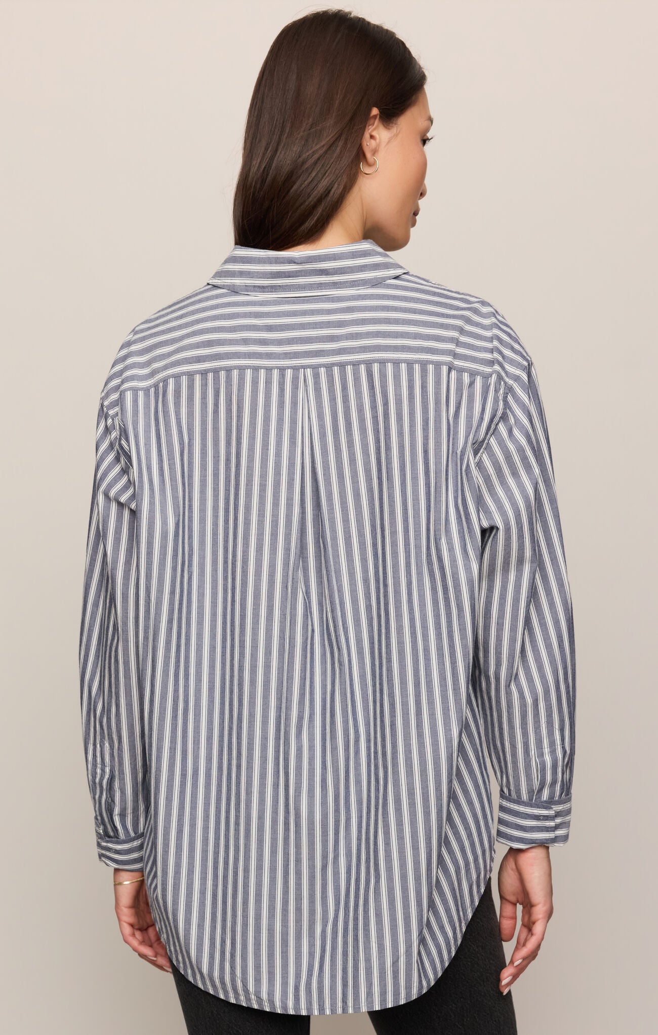 Person wearing a gray and white striped shirt against a beige background
