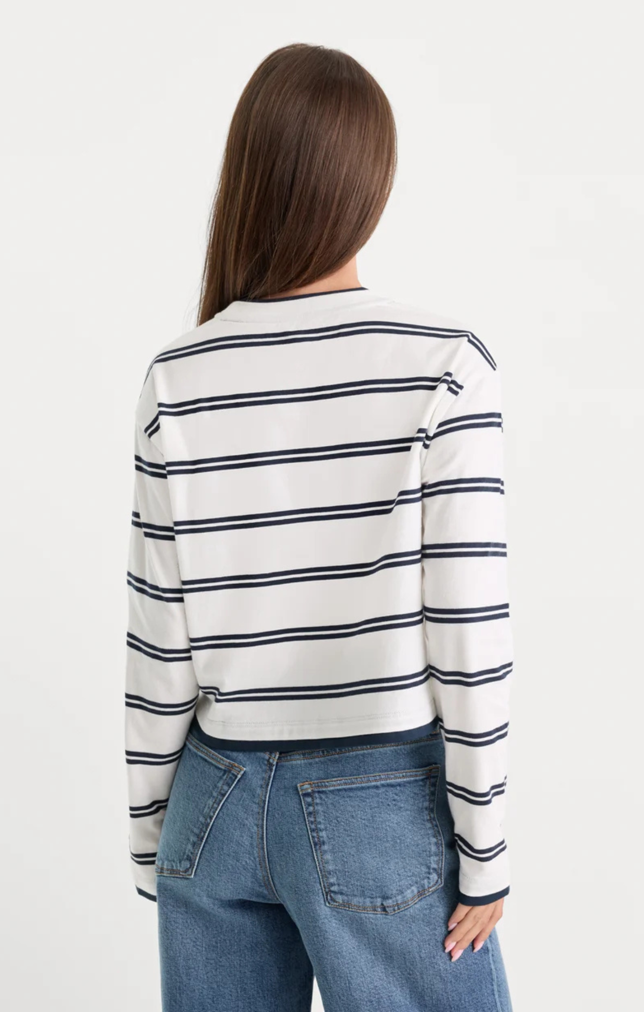 Woman wearing a striped long-sleeve shirt and jeans on a white background