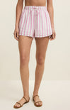 Person wearing pink and white striped shorts on a beige background