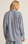 Person wearing a blue striped shirt and pants on a beige background