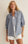 Woman wearing a blue striped shirt and white shorts on a beige background