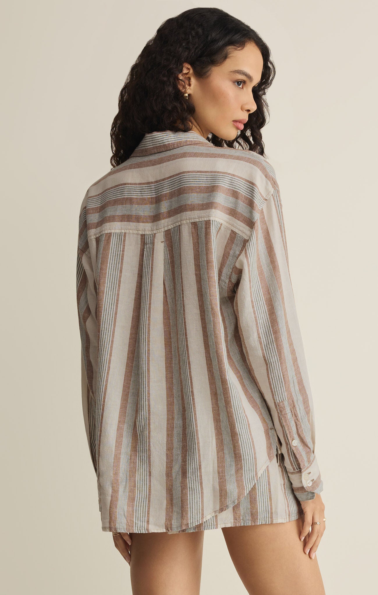Woman wearing a striped shirt against a beige background