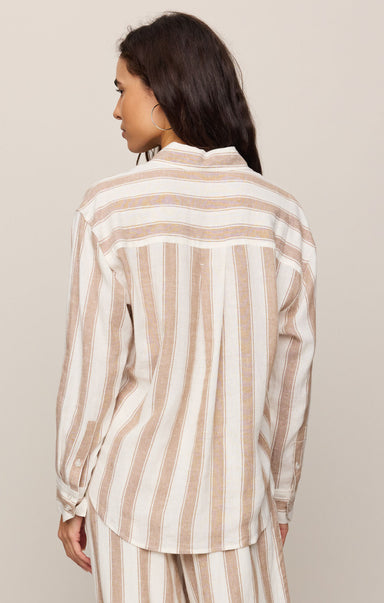 Woman wearing a beige and white striped shirt against a beige background