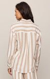 Woman wearing a beige and white striped shirt against a beige background