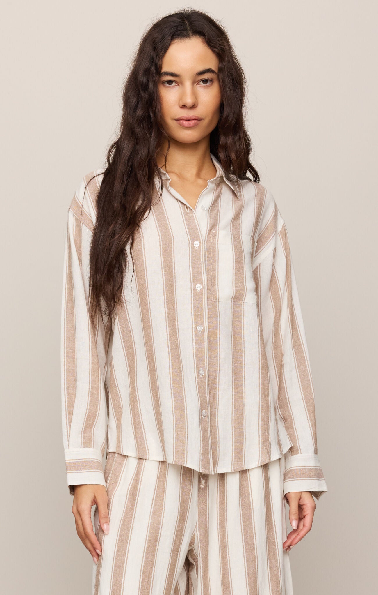 Woman wearing a striped pajama set against a plain background