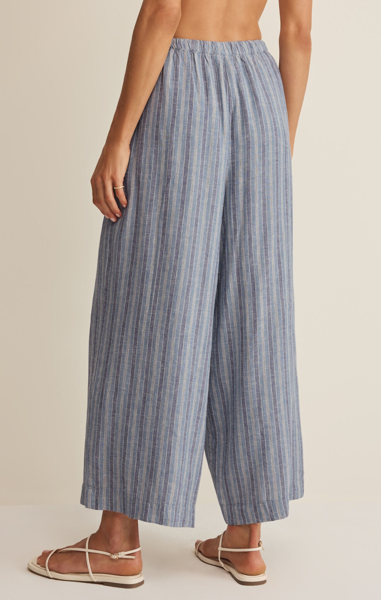 Blue striped wide-leg pants worn by a person on a beige background