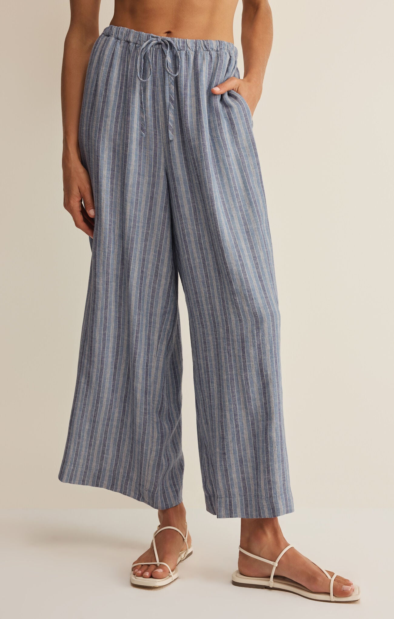 Person wearing blue striped wide-leg pants on a beige background