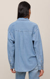 Person wearing a light blue denim jacket on a beige background