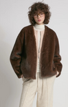 Person wearing a brown fur coat with a plain background